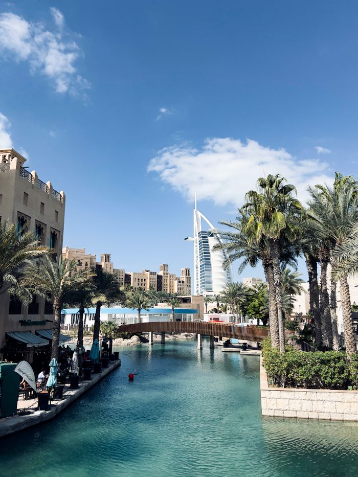 View of Burj Al Arab with palm trees and Souk Madinat Jumeirah in Dubai. Iconic UAE skyline.